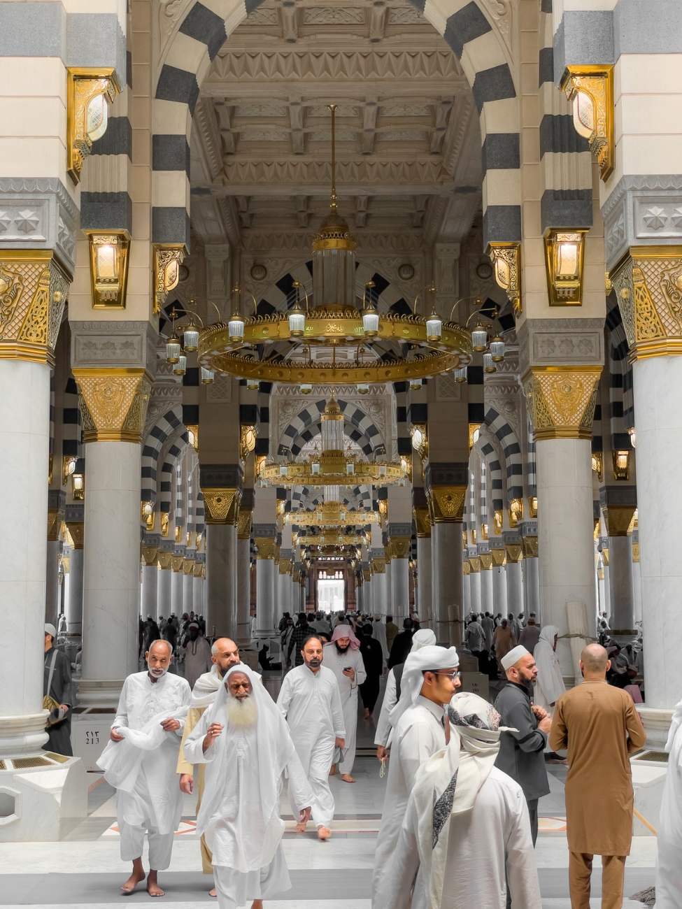 Pilgrims walking through the ornate interior of An Nabawi Mosque